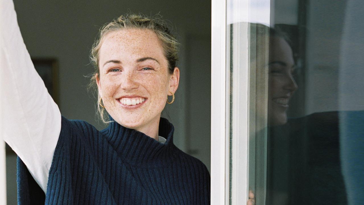 Ung kvinna ler mot betraktaren i ett fönster