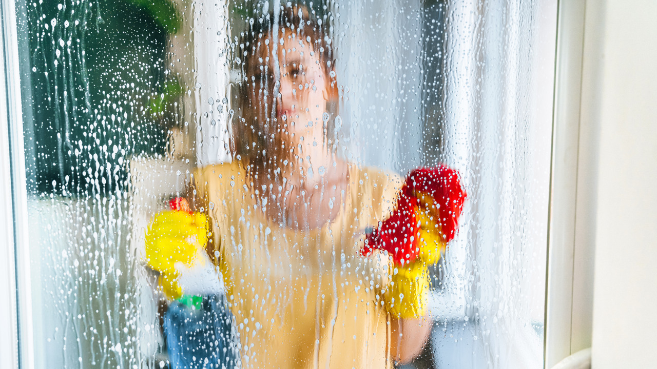Ung kvinna tvättar fönster